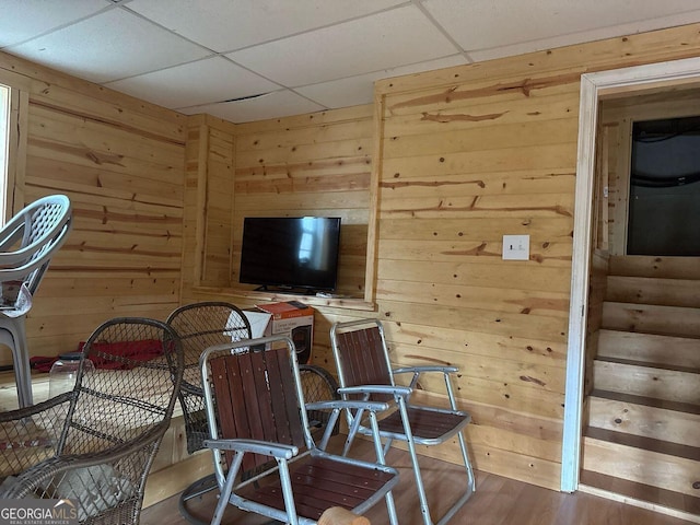 interior space with a paneled ceiling, hardwood / wood-style floors, and wood walls