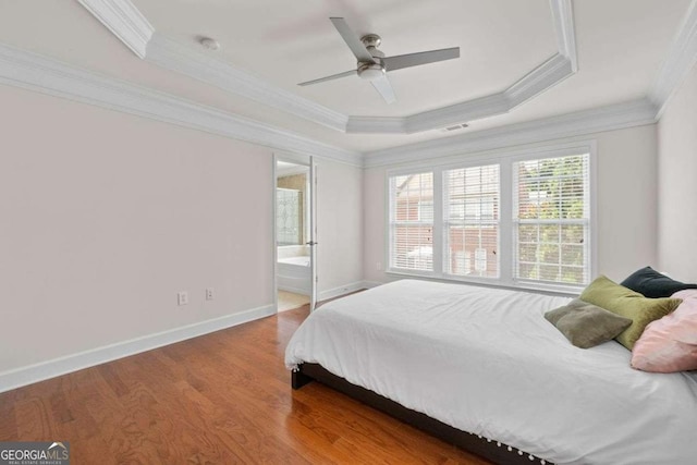 bedroom featuring a raised ceiling, ornamental molding, hardwood / wood-style flooring, and ensuite bathroom