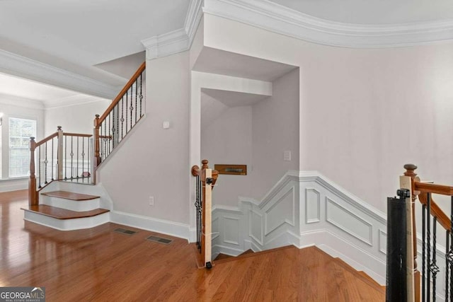 stairs with ornamental molding and hardwood / wood-style floors