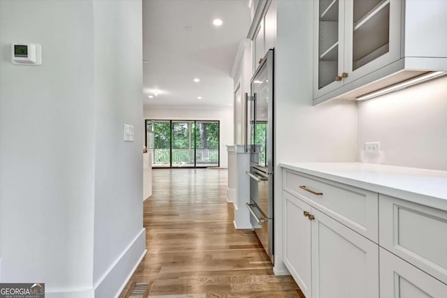 hallway with crown molding and light hardwood / wood-style floors