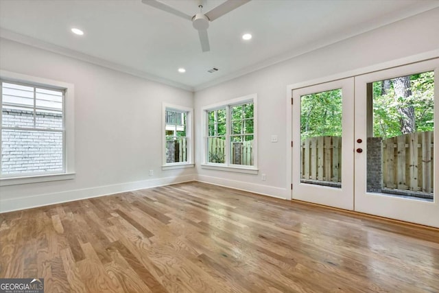 unfurnished room featuring hardwood / wood-style flooring, ornamental molding, a wealth of natural light, and french doors