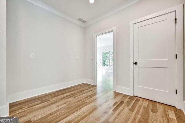 spare room featuring ornamental molding and light hardwood / wood-style floors