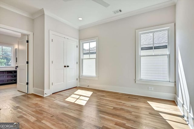 unfurnished bedroom featuring crown molding, light hardwood / wood-style flooring, a closet, and ceiling fan