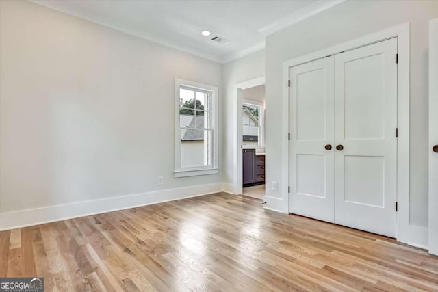 unfurnished bedroom with crown molding, a closet, and light wood-type flooring