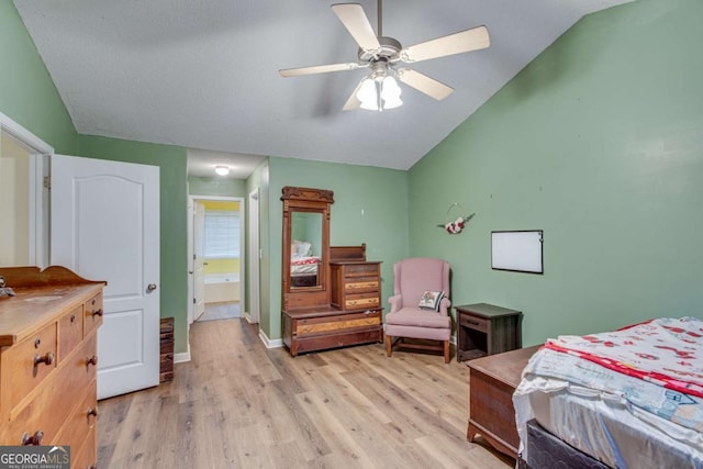 bedroom featuring ceiling fan, ensuite bathroom, vaulted ceiling, and light wood-type flooring