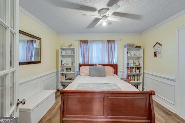 bedroom with crown molding, wood-type flooring, a textured ceiling, and ceiling fan