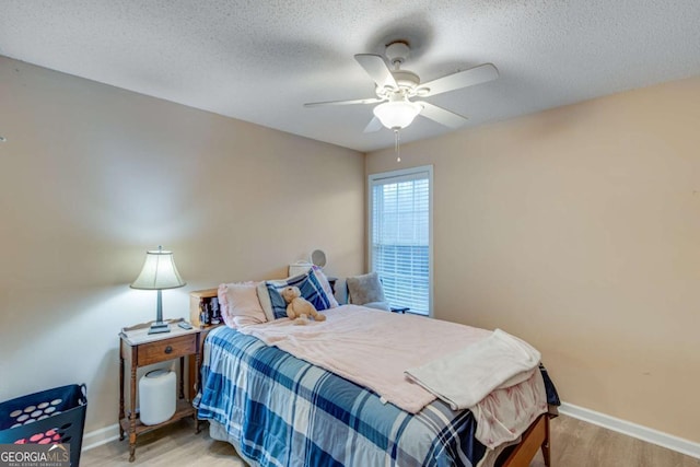 bedroom with ceiling fan, light hardwood / wood-style flooring, and a textured ceiling