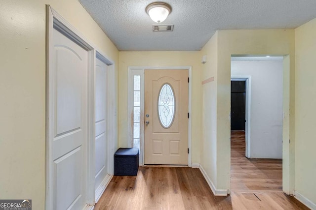 entryway with a textured ceiling and light hardwood / wood-style flooring