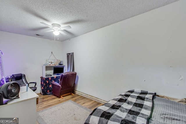 bedroom featuring a textured ceiling, light hardwood / wood-style floors, and ceiling fan