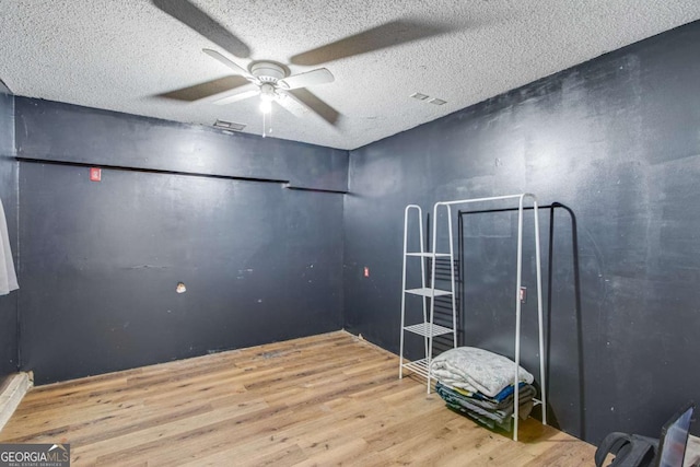 interior space featuring ceiling fan, a textured ceiling, and light wood-type flooring