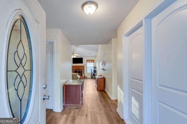 corridor featuring a textured ceiling and light hardwood / wood-style flooring