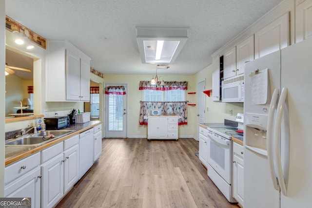 kitchen featuring sink, white appliances, white cabinetry, light hardwood / wood-style floors, and a textured ceiling