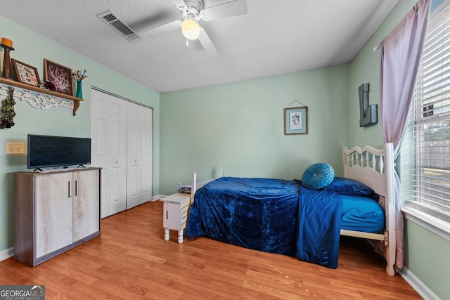 bedroom featuring multiple windows, a closet, ceiling fan, a textured ceiling, and light hardwood / wood-style flooring