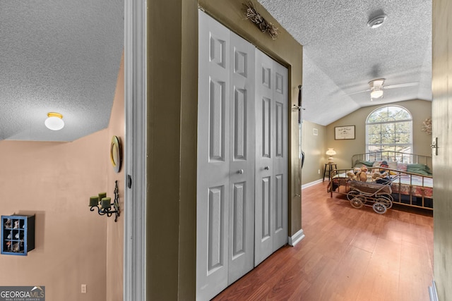 hall with vaulted ceiling and wood-type flooring