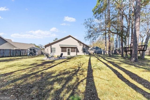 back of property with a storage shed, a lawn, and an outdoor fire pit