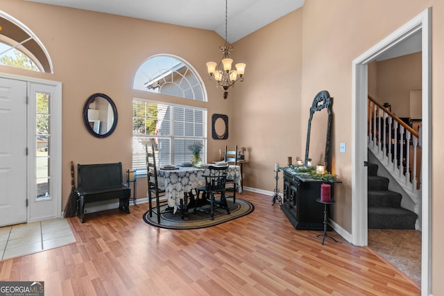 entryway with high vaulted ceiling, an inviting chandelier, and light hardwood / wood-style floors