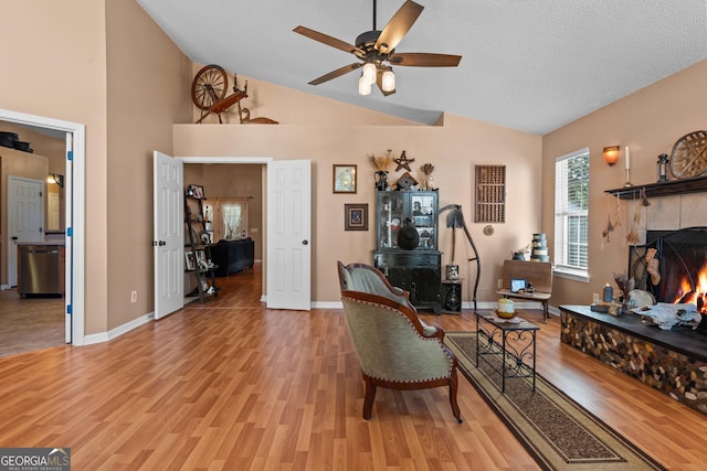 living room featuring lofted ceiling, a fireplace, light hardwood / wood-style floors, and a textured ceiling