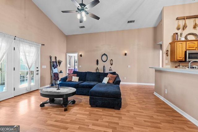 living room with ceiling fan, high vaulted ceiling, and light hardwood / wood-style floors