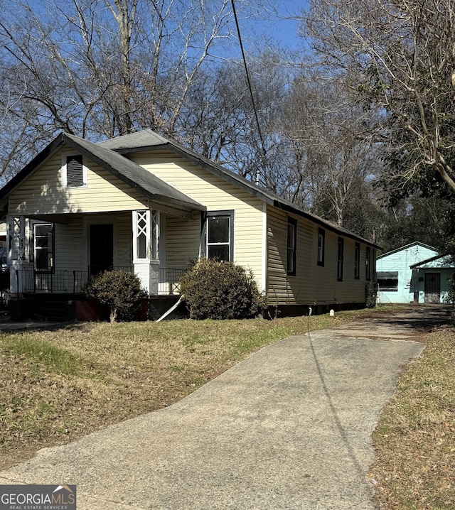 view of property exterior with a yard, a garage, an outdoor structure, and a porch