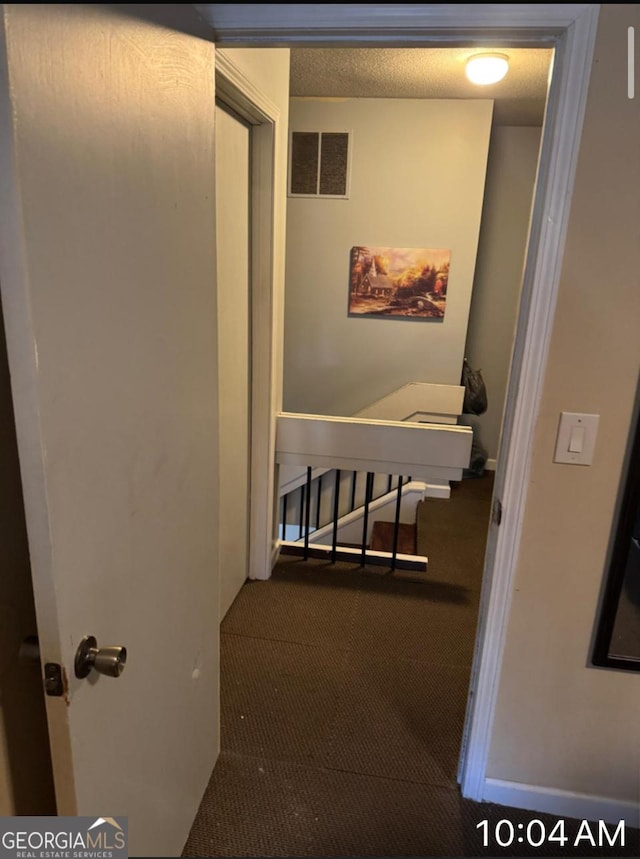 hall with carpet flooring and a textured ceiling