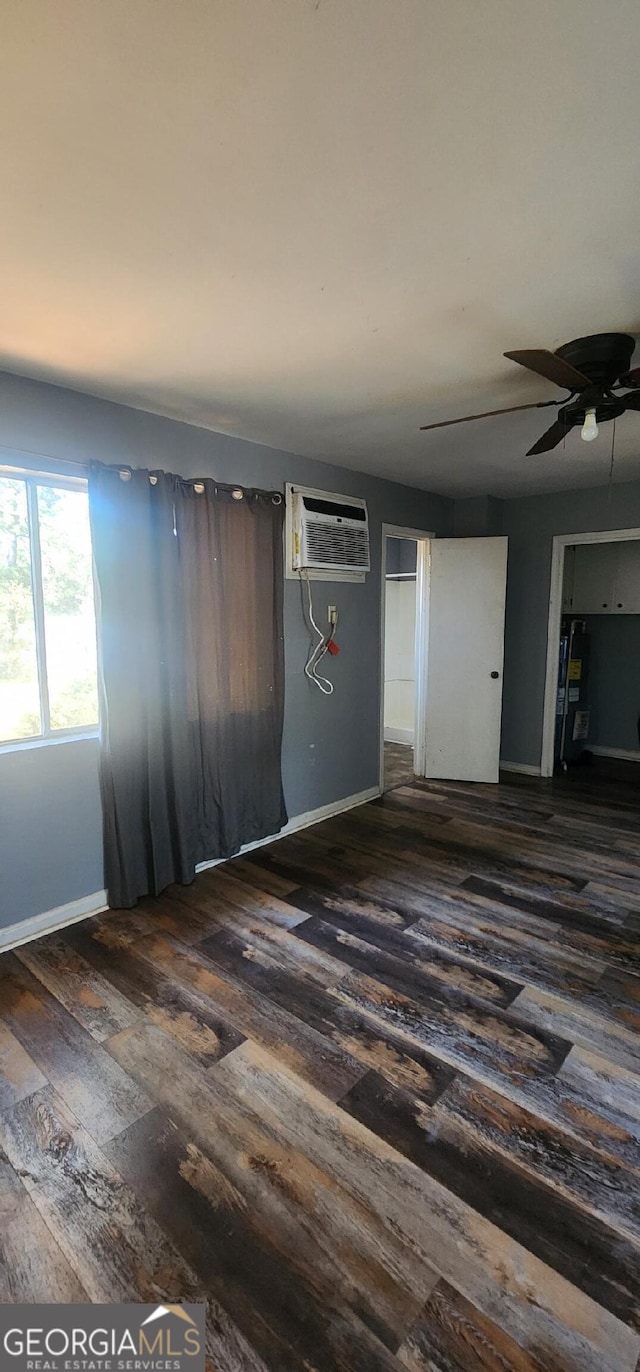 unfurnished room featuring dark hardwood / wood-style flooring, an AC wall unit, and ceiling fan