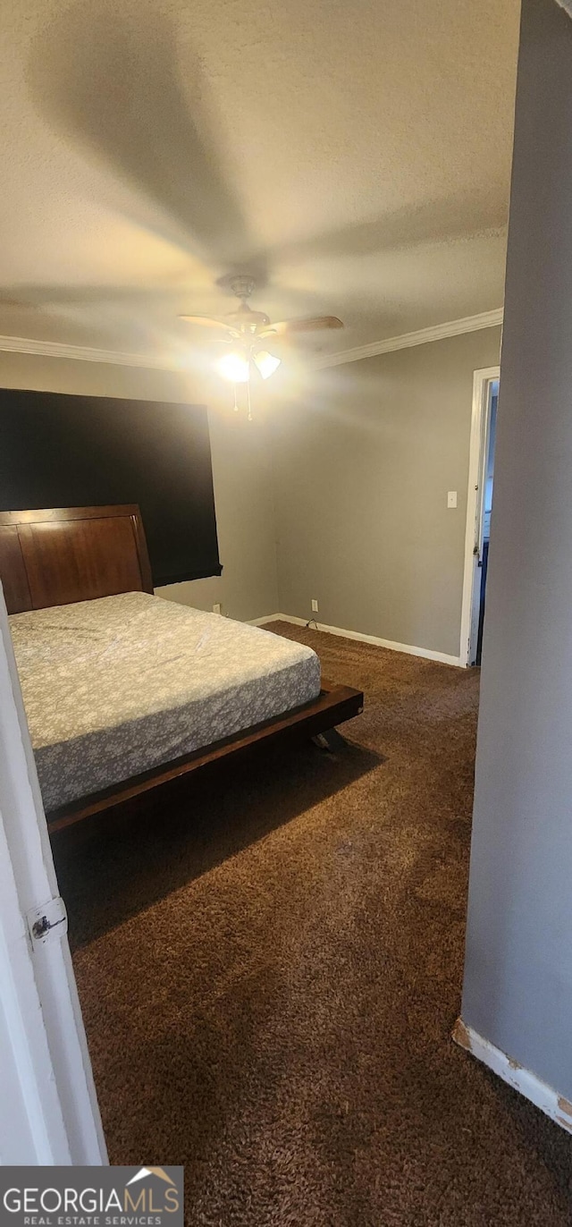 unfurnished bedroom featuring crown molding, ceiling fan, and dark colored carpet