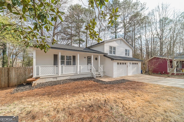 tri-level home featuring a garage, covered porch, fence, and concrete driveway