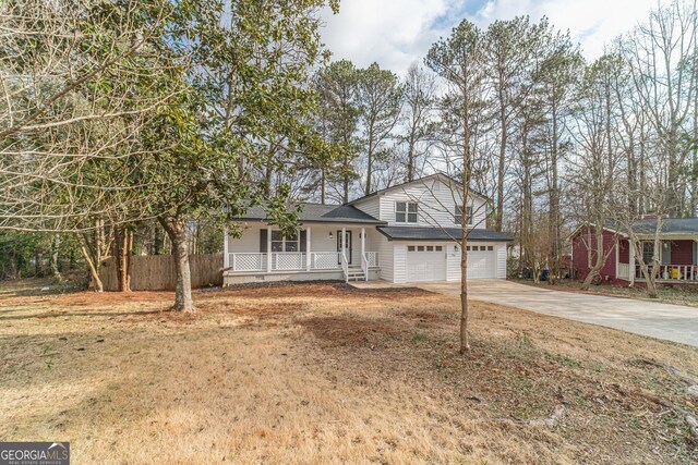 split level home featuring a garage, covered porch, and a front lawn