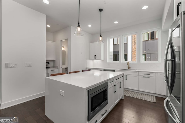 kitchen with pendant lighting, sink, stainless steel appliances, a center island, and white cabinets