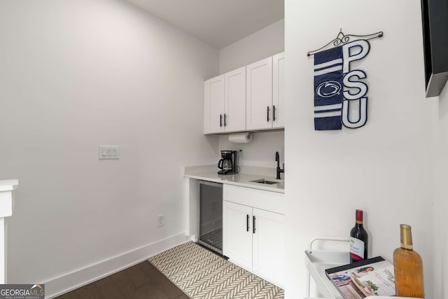 bar featuring white cabinetry, sink, and light hardwood / wood-style floors