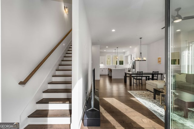 stairway featuring sink, hardwood / wood-style flooring, and ceiling fan with notable chandelier