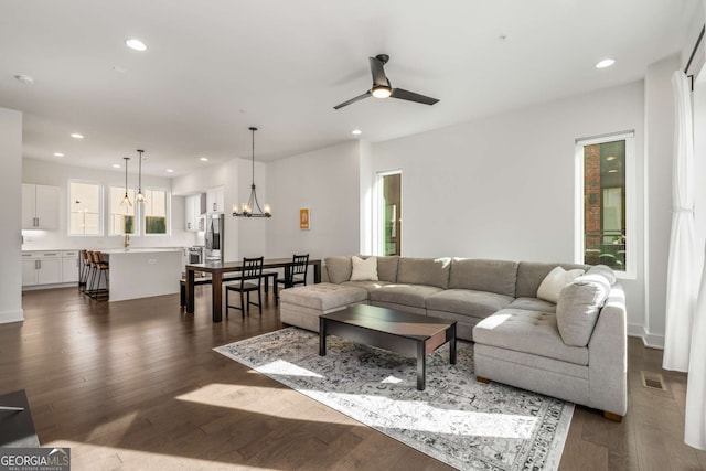 living room featuring sink, ceiling fan with notable chandelier, and dark hardwood / wood-style flooring