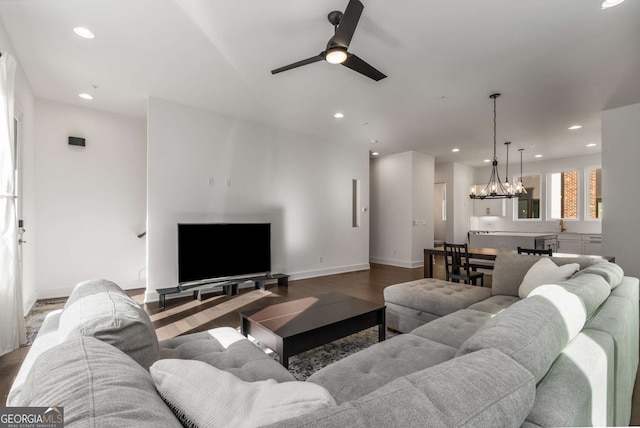 living room with ceiling fan with notable chandelier and dark hardwood / wood-style floors