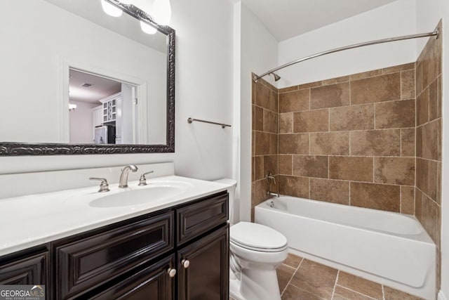 full bathroom featuring tiled shower / bath, vanity, and toilet