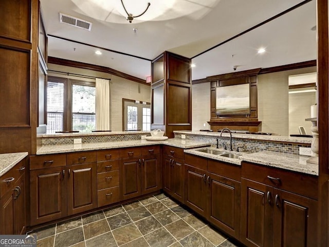 kitchen featuring tasteful backsplash, light stone countertops, sink, and kitchen peninsula