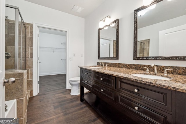 bathroom with vanity, a tile shower, hardwood / wood-style floors, and toilet