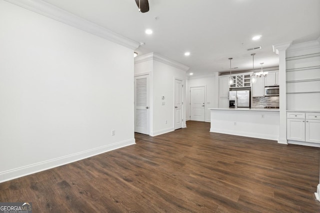 unfurnished living room featuring ceiling fan with notable chandelier, dark wood-type flooring, and ornamental molding