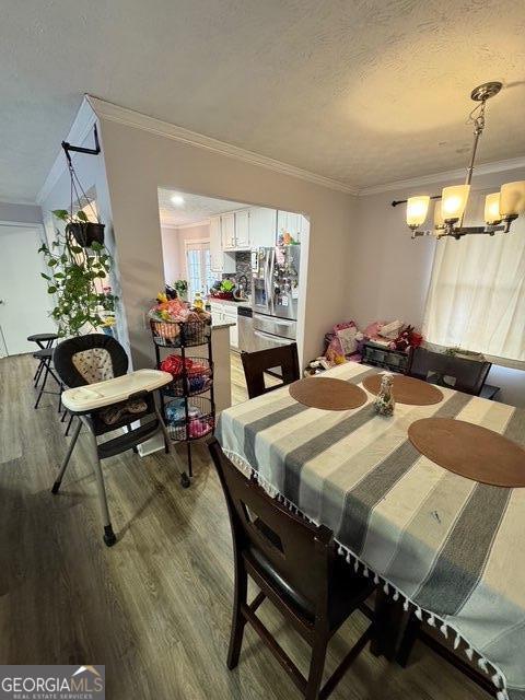 dining room with crown molding, wood-type flooring, and a chandelier