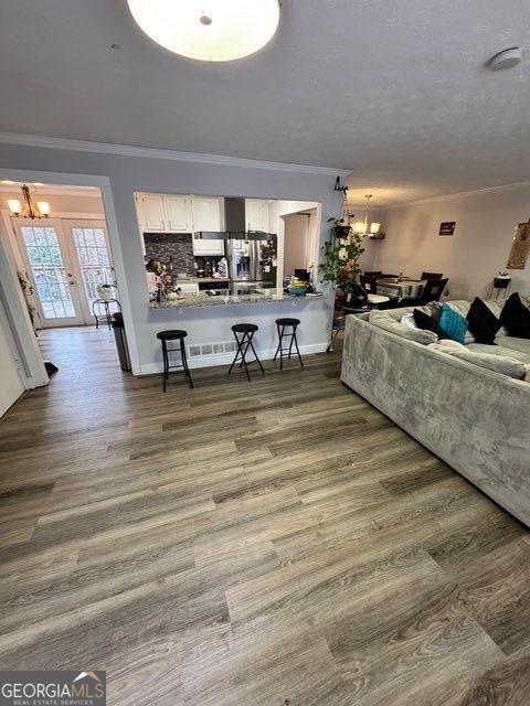 living room featuring an inviting chandelier, ornamental molding, and dark wood-type flooring