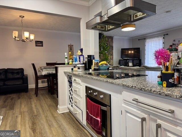 kitchen with crown molding, white cabinetry, hanging light fixtures, black electric stovetop, and oven