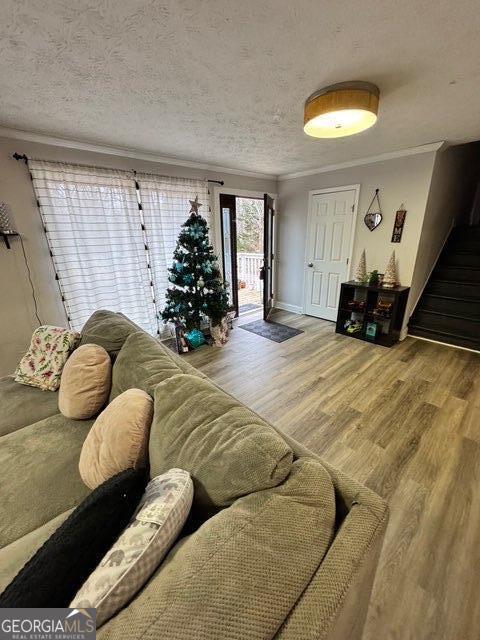 living room with hardwood / wood-style flooring, crown molding, and a textured ceiling