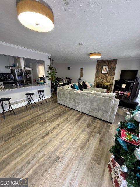 living room featuring hardwood / wood-style flooring, ornamental molding, a fireplace, and a textured ceiling