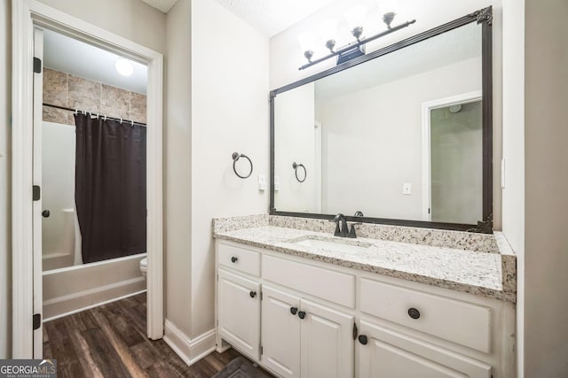 full bathroom featuring hardwood / wood-style flooring, vanity, shower / tub combo, toilet, and a textured ceiling