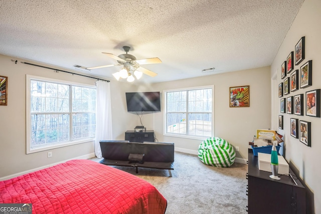 carpeted bedroom featuring multiple windows, a textured ceiling, and ceiling fan