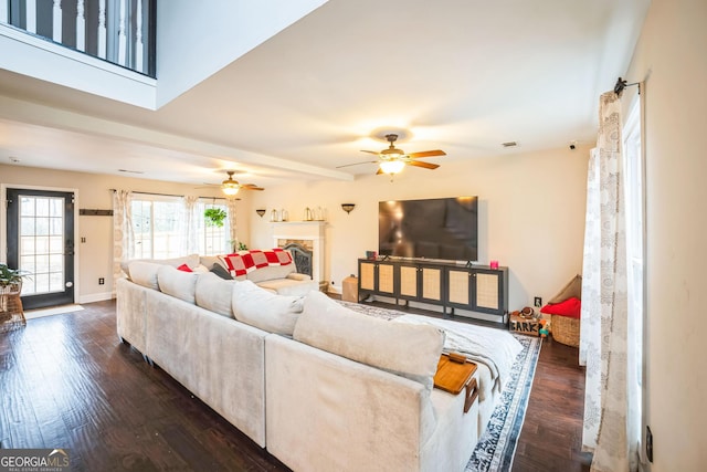 living room featuring dark hardwood / wood-style flooring, a premium fireplace, and ceiling fan