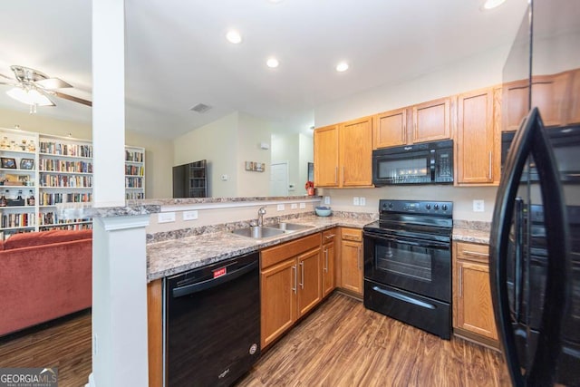 kitchen featuring dark wood-type flooring, kitchen peninsula, sink, and black appliances