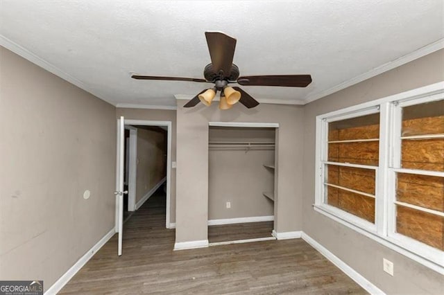 unfurnished bedroom featuring dark hardwood / wood-style floors, ornamental molding, a closet, and ceiling fan