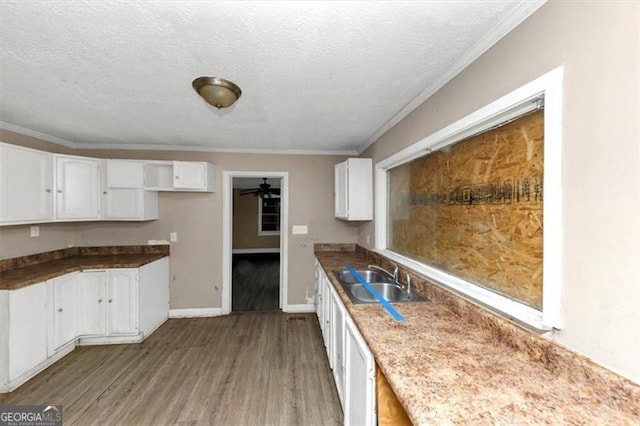 kitchen featuring sink, white cabinetry, ornamental molding, a textured ceiling, and light wood-type flooring