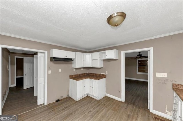 kitchen featuring ornamental molding, light hardwood / wood-style floors, a textured ceiling, and white cabinets