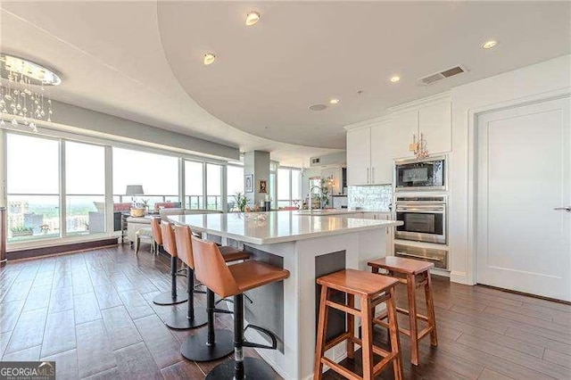 kitchen featuring built in microwave, a breakfast bar, white cabinetry, stainless steel oven, and a center island